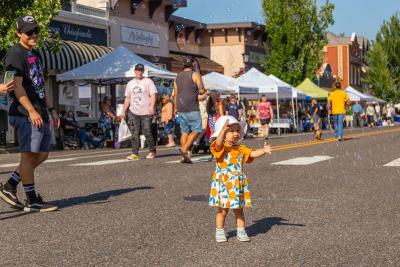 A toddler reaches for bubbles in downtown Troutdale during First Friday